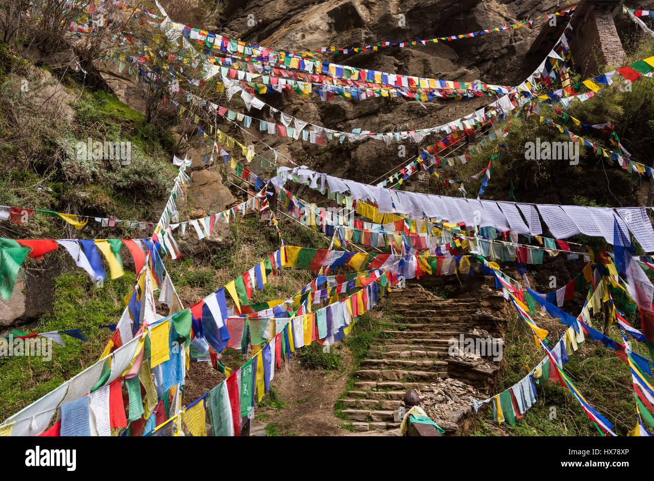 Prayer flags over the trail to the Tiger's Nest Monastery, or Taktsang Goemba, a Himalayan Bhuddist monastery perched on sheer cliffs 900 meters above Stock Photo