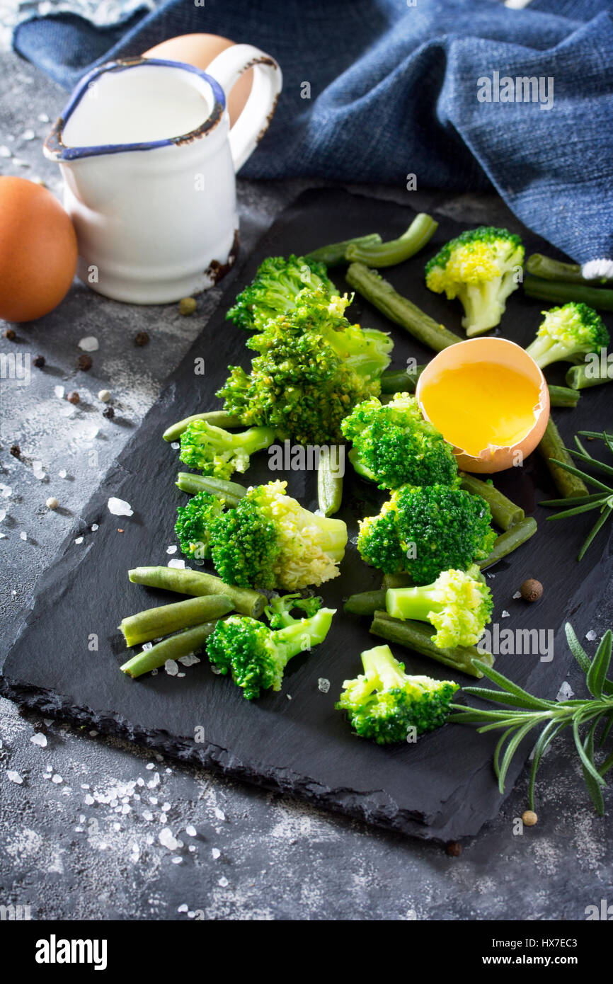 Fresh green broccoli, green beans, milk, rosemary and eggs on a slate