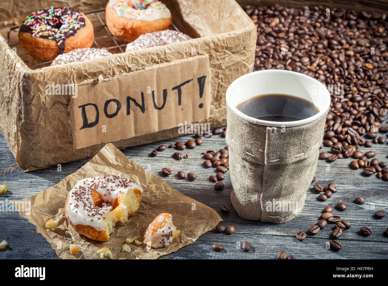 Box full of donuts with coffee on old wooden table Stock Photo - Alamy