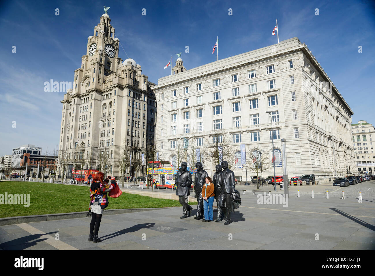 Tourists pose for photographs with the statues of the world famous 1960's group, The Beatles. Statues of the famous Liverpool Group The Beatles situat Stock Photo