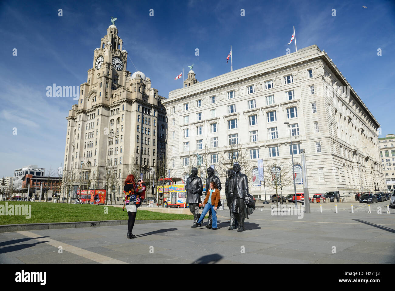 Tourists pose for photographs with the statues of the world famous 1960's group, The Beatles. Statues of the famous Liverpool Group The Beatles situat Stock Photo