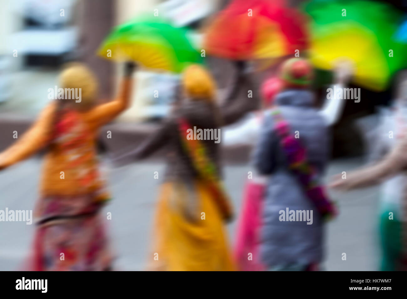 Girls in bright clothes, group of Hare Krishna movement singing and dancing in the streets of the city with the words Hare Krishna. Abstract defocused motion blurred Stock Photo