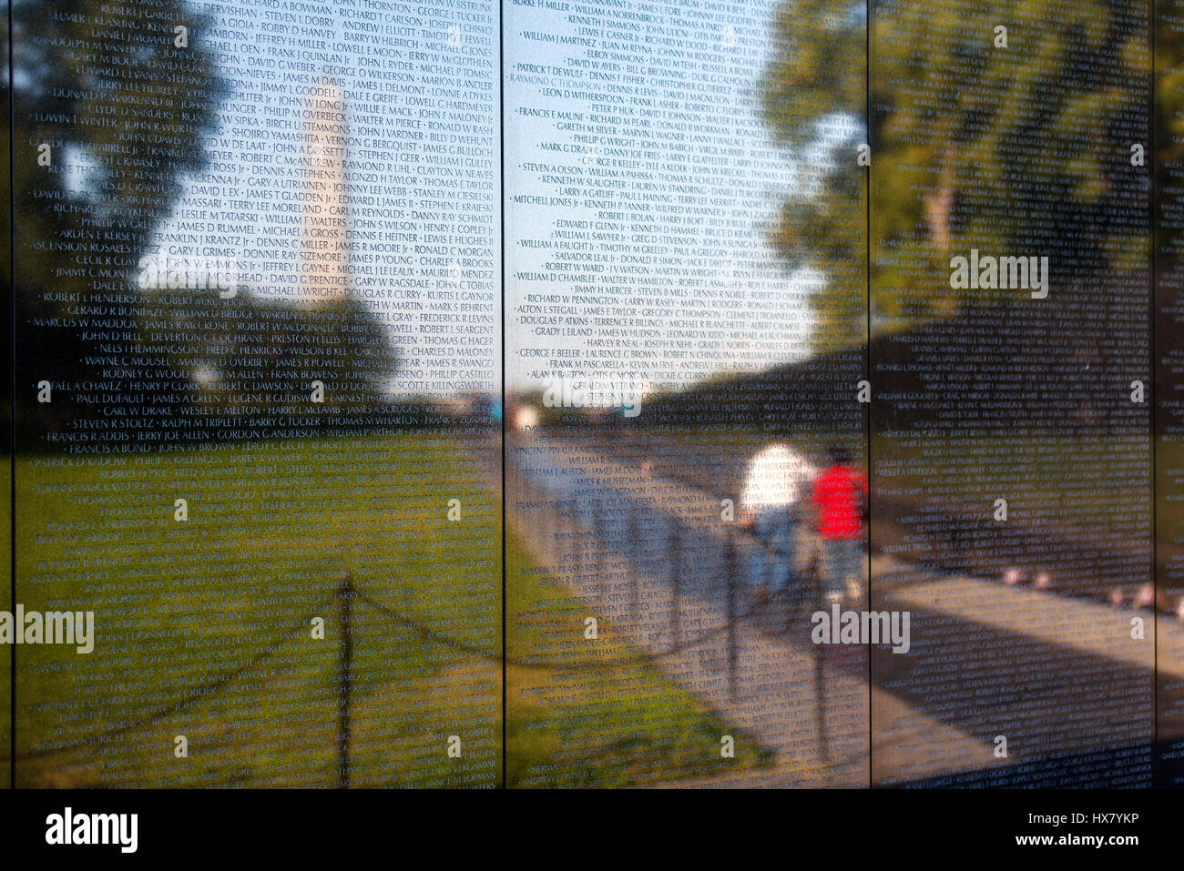 The Vietnam veterans war memorial wall in Washington DC, usa.the wall reflects a couple walking away and the Washington monument in the background Stock Photo