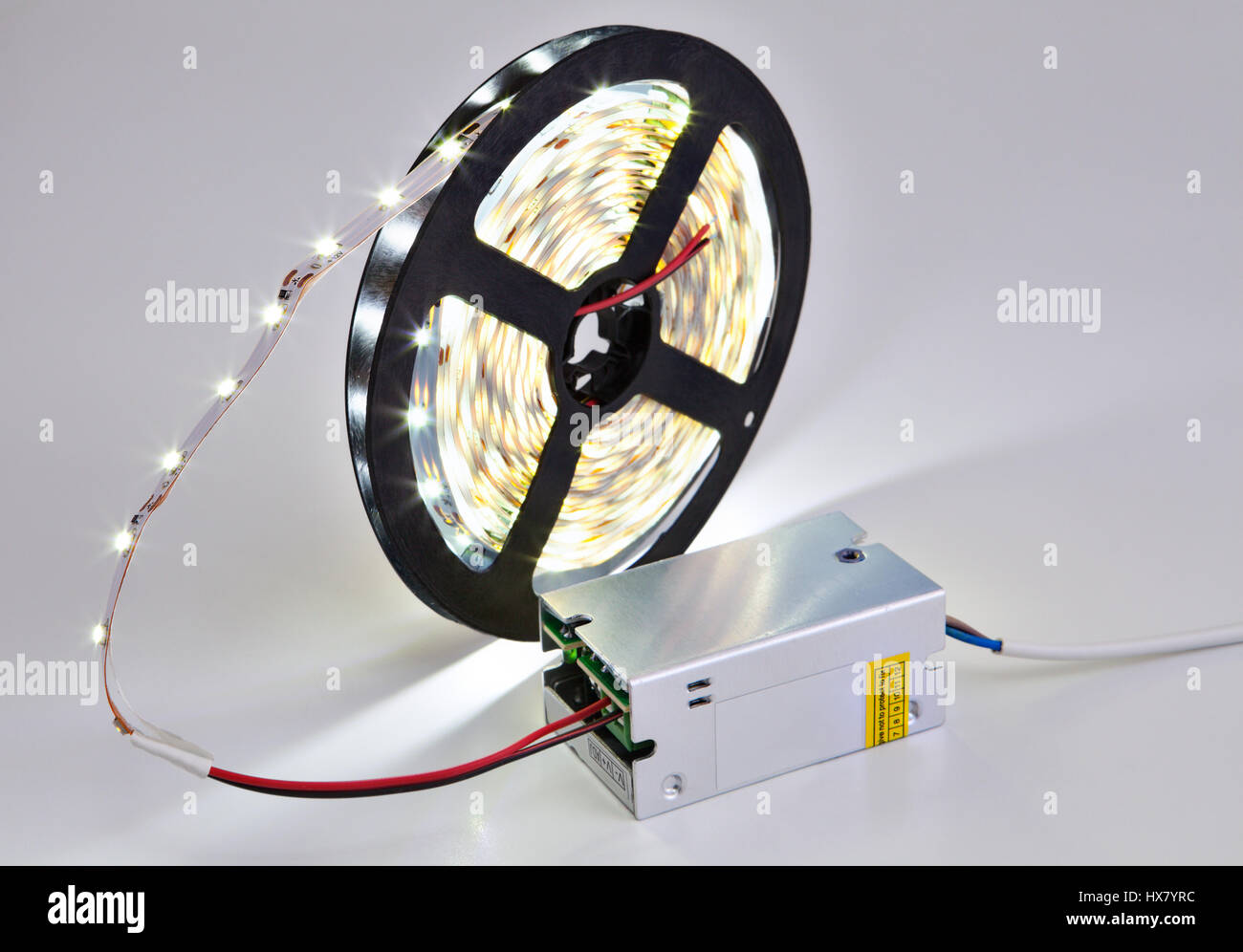 Spool of luminous LED strip light connected to Power Supply Adapter Driver. Stock Photo