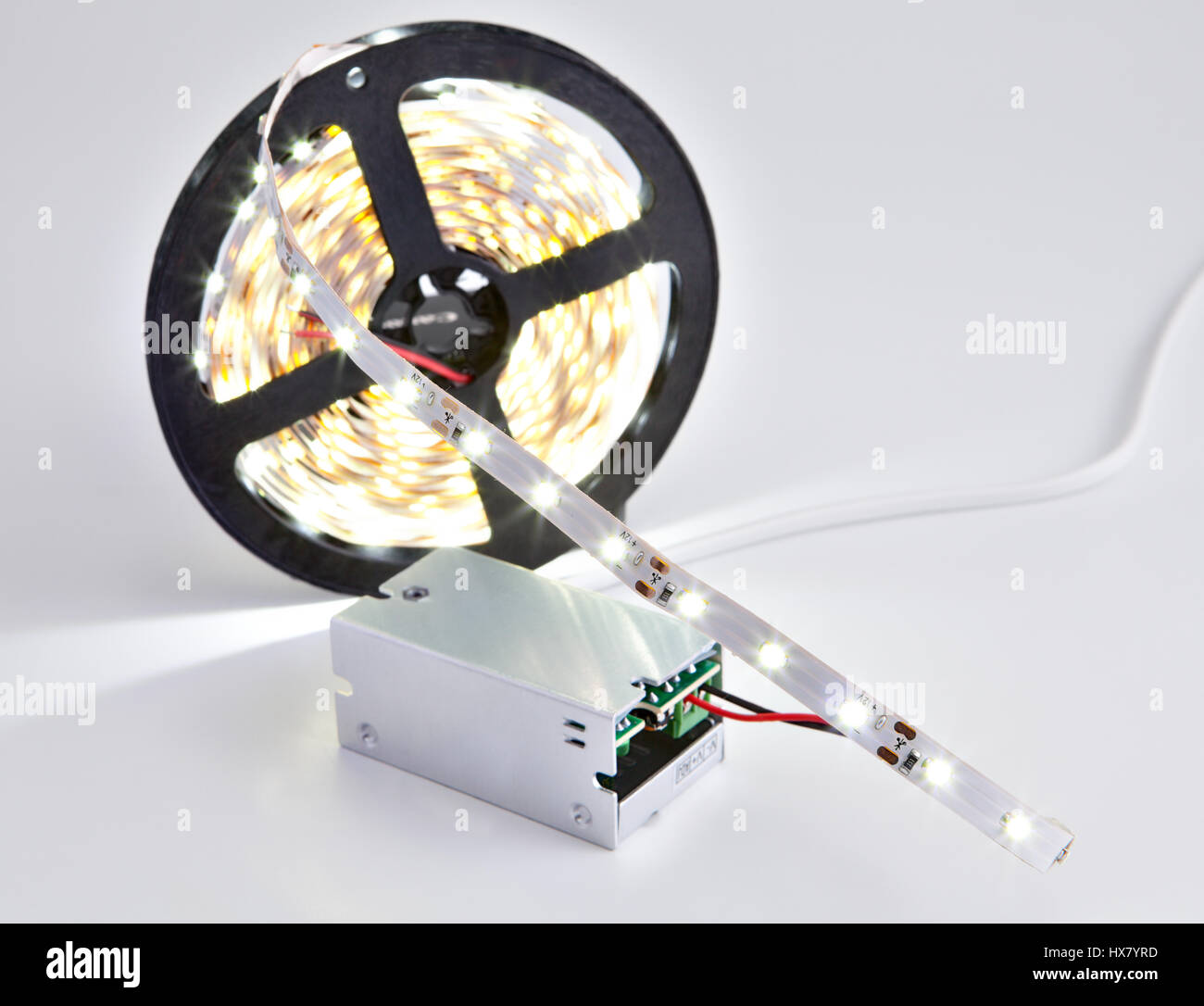 Reel of luminous LED strip light connected to voltage transformer. Stock Photo