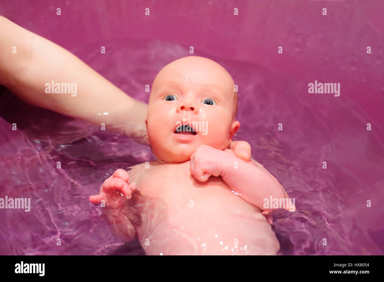 newborn baby swim in blue bathtub holding mother hand Stock Photo Alamy