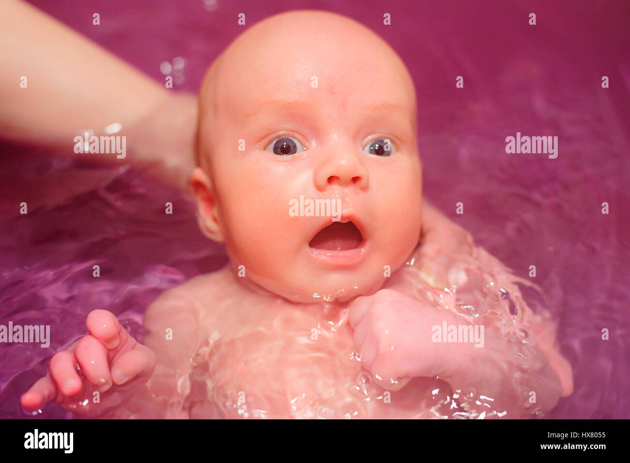 newborn baby swim in blue bathtub holding mother hand Stock Photo Alamy