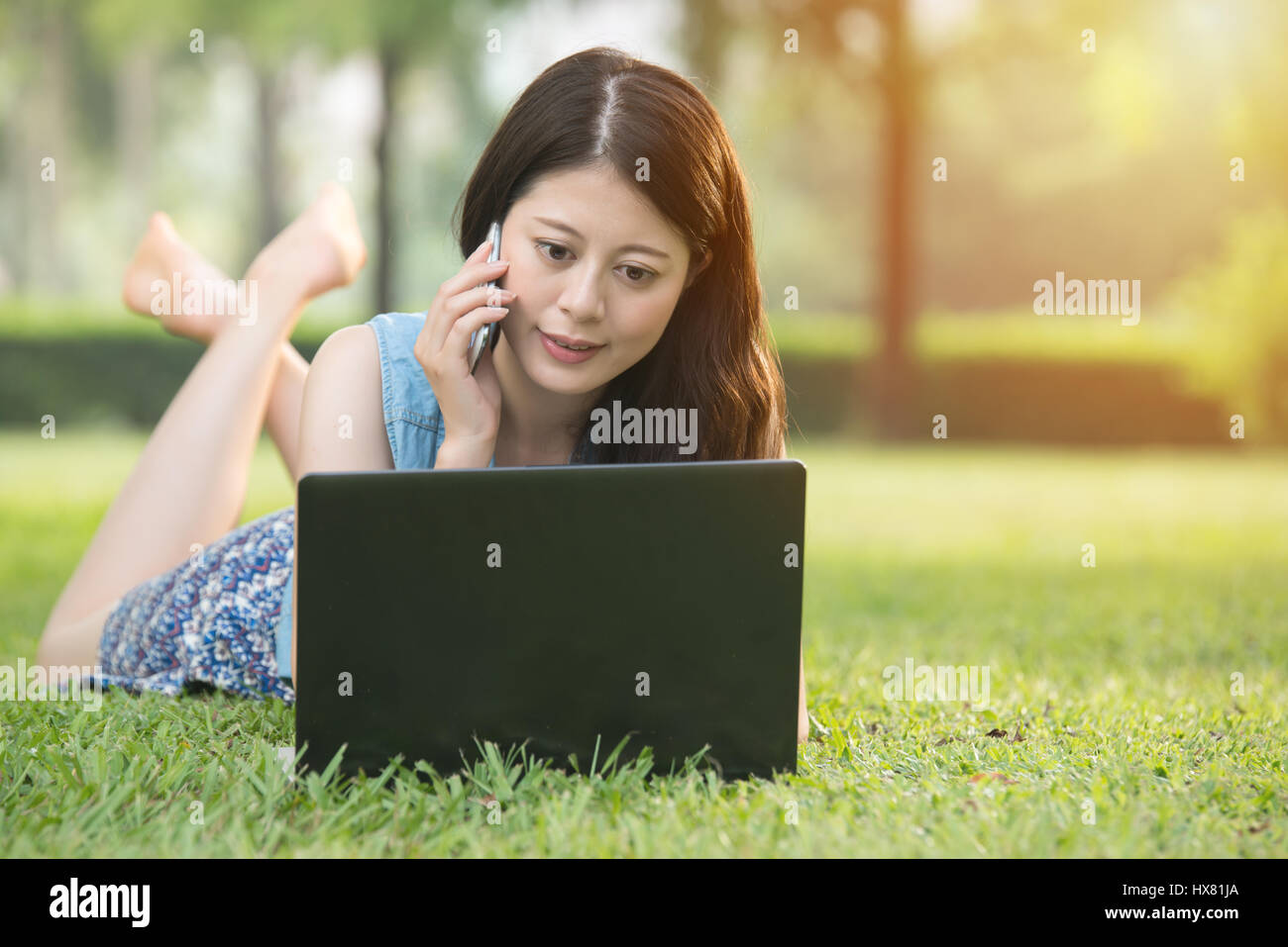 beautiful asian woman using computer on grass in outdoor park. nature ...