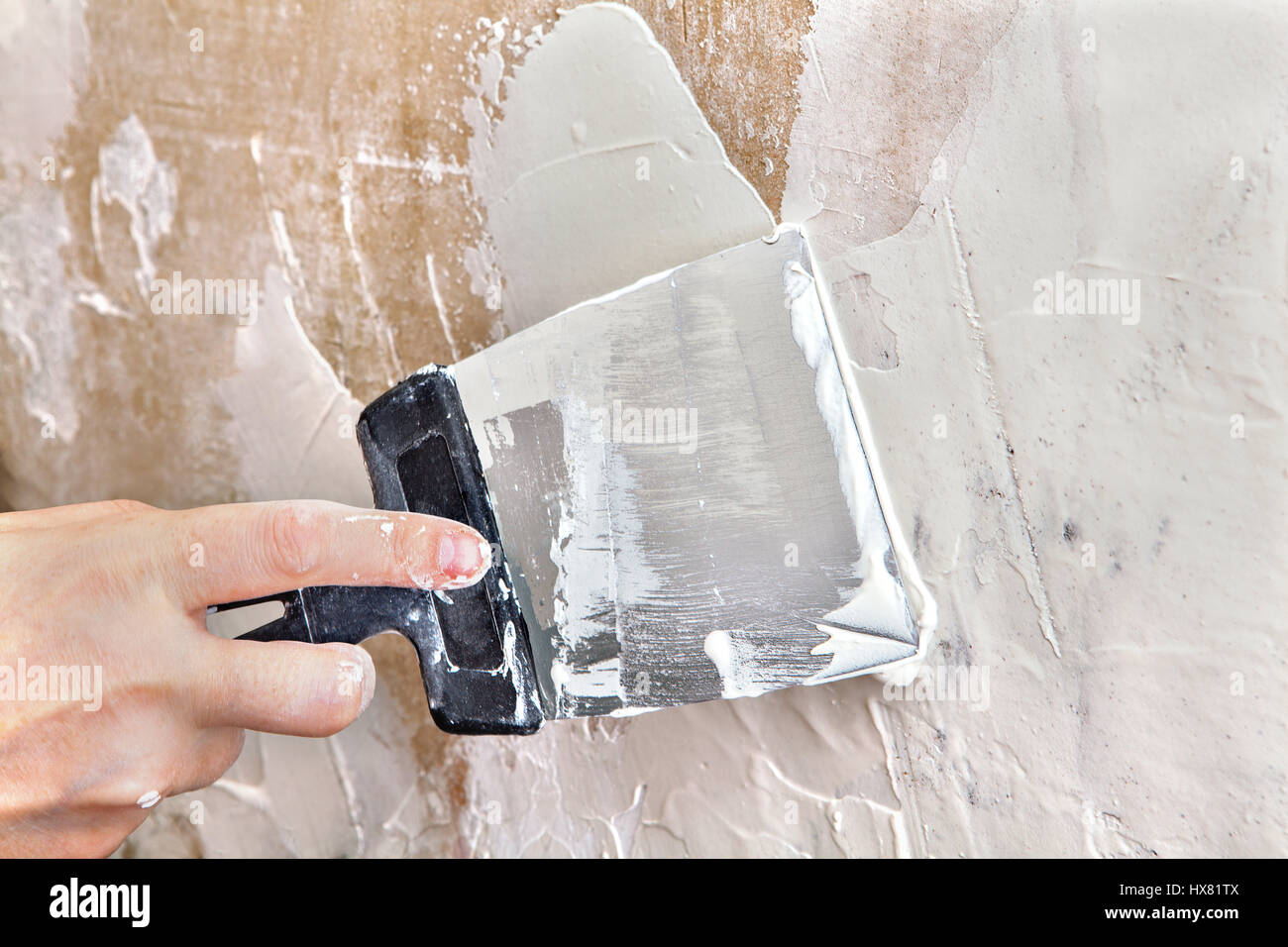 Painting worker puttied wall using a paint spatula hand closeup. Stock Photo