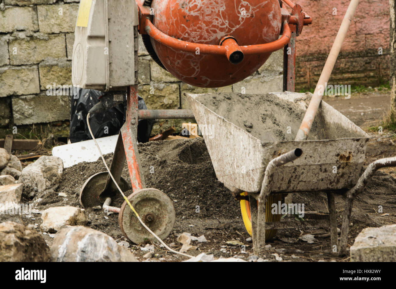 Cement mixer, wheelbarrow and shovel on the construction place Stock