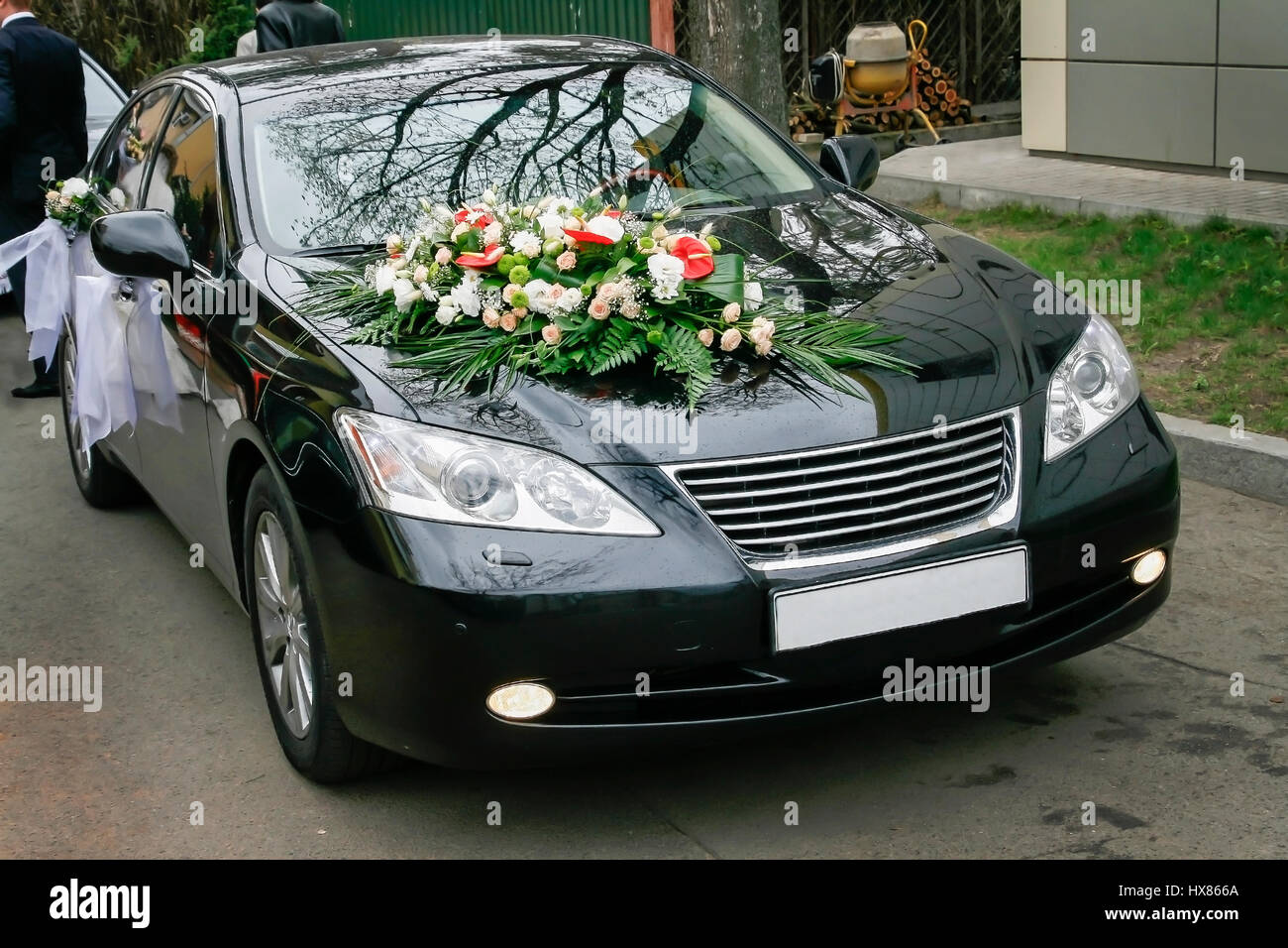 The hood of a black car is decorated with a bouquet of flowers in