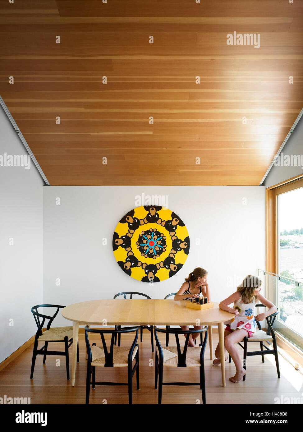 Owner's daughter and friend in the upstairs dining room. Floating House, Private Island, Georgian Bay, Lake Huron, Canada. Architect: MOS Architects, Stock Photo