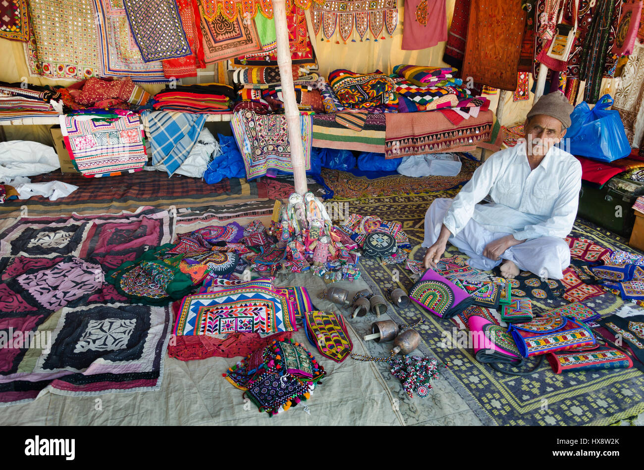 KUTCH, GUJARAT, INDIA - DECEMBER 27, 2016: An unidentified handicraft vendor in his traditional street shop selling colourful embroidery items. Stock Photo