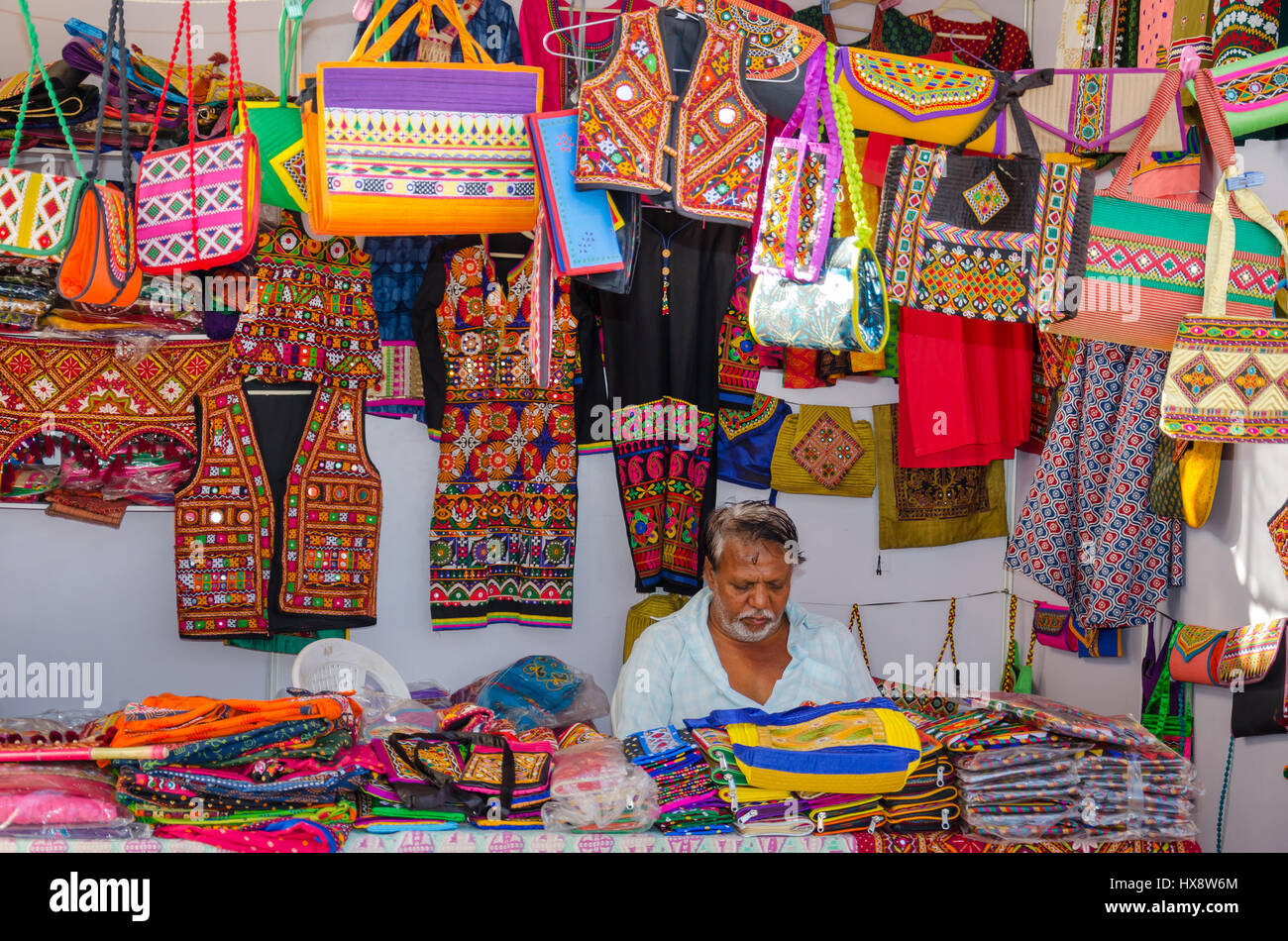 KUTCH, GUJARAT, INDIA - DECEMBER 27, 2016: An unidentified handicraft vendor in his traditional street shop selling colourful embroidery items. Stock Photo