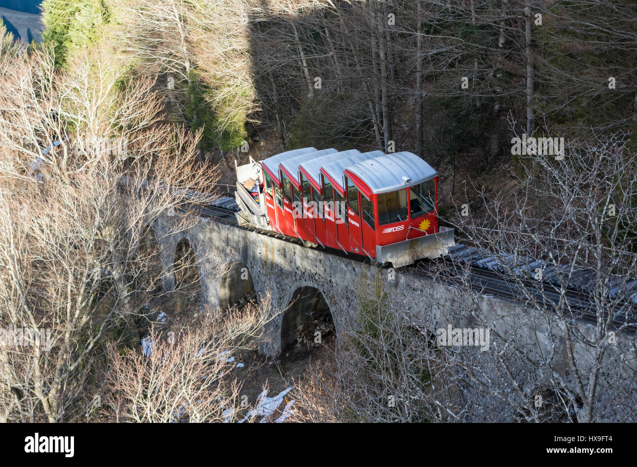 Red car of the old Schlattli-Stoos funicular approaching its top station on a steep viaduct. Stoos, Schwyz, Switzerland. Stock Photo
