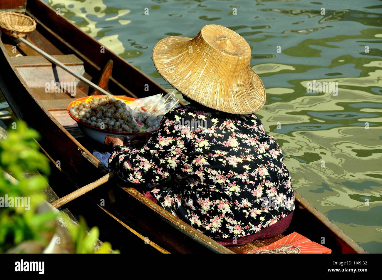 Amphawa, Thailand - December 17, 2010:  Thai woman wearing a straw hat sits in her boat selling fish balls at the Amphawa floating market Stock Photo