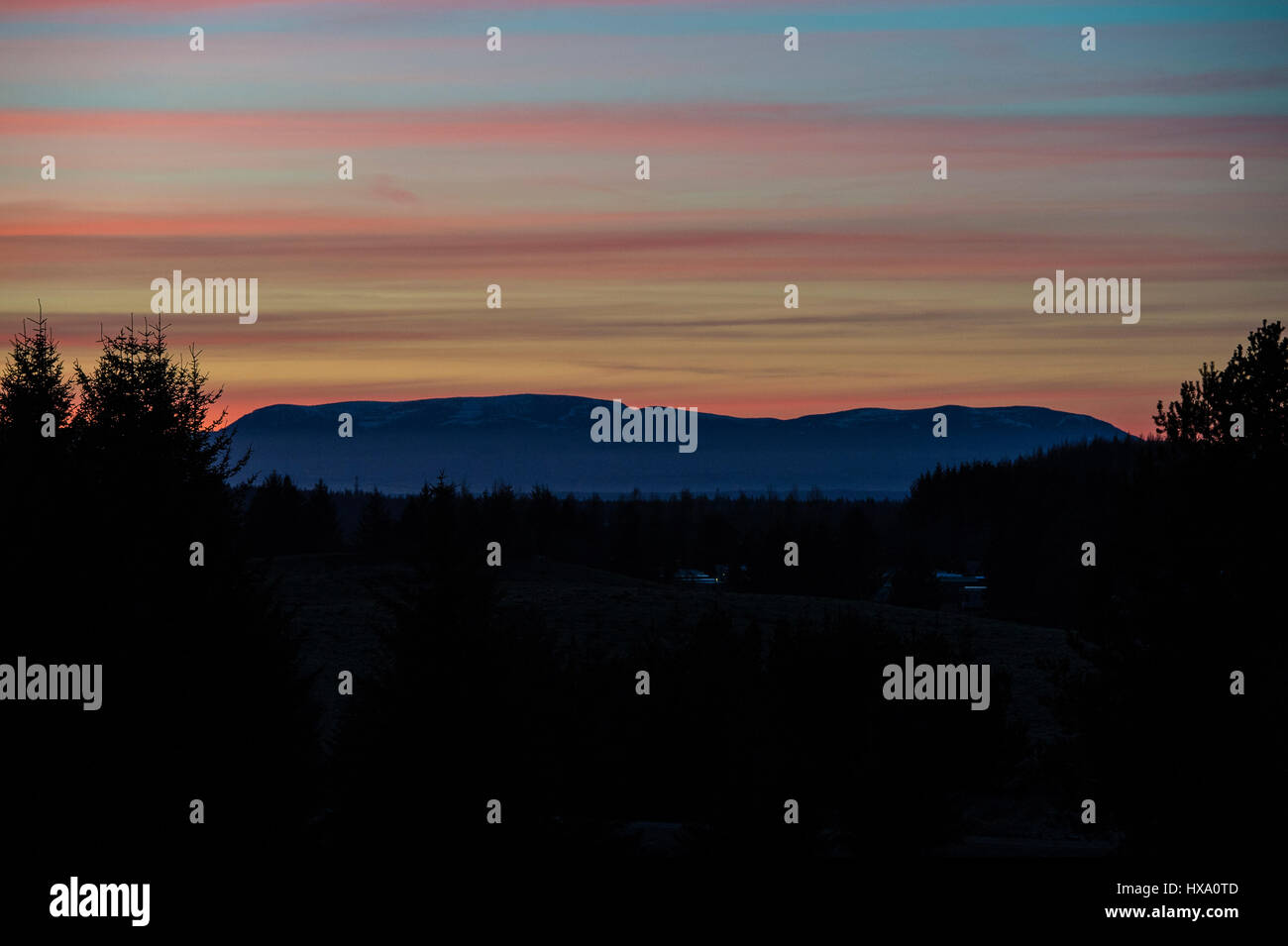 The sun sets behind Ben Wyvis in the Scottish Highlands, near Inverness on the first day of British Summer Time & another day of glorious sunshine and clear blue skies in the Highlands. Stock Photo