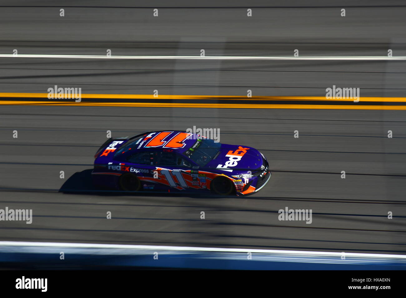 Denny Hamlin makes his way to the start finish line of Daytona International Speedway going 180mph in his Fedex Livery Toyota Camry. Stock Photo