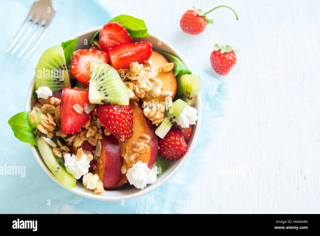 Fresh fruit salad with homemade granola, feta cheese and honey on white