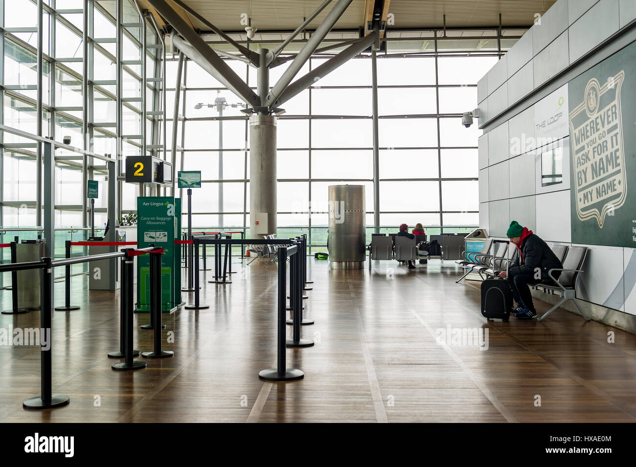 Birmingham Airport's (BHX), United Kingdom departure lounge with a man sitting on his own waiting to board a flight. Stock Photo