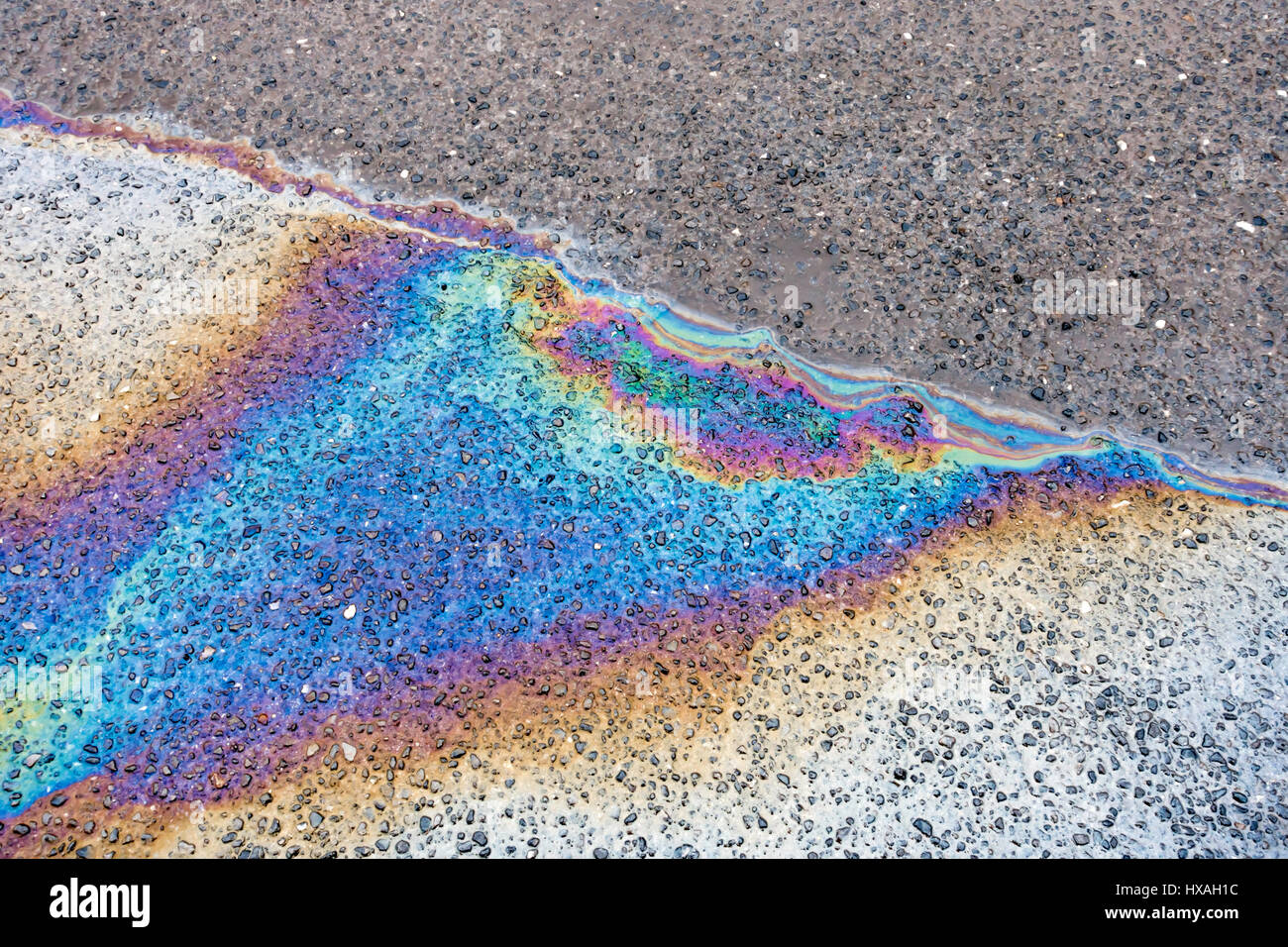 Rainbow coloured oil spill on wet Tarmac road surface Stock Photo Alamy