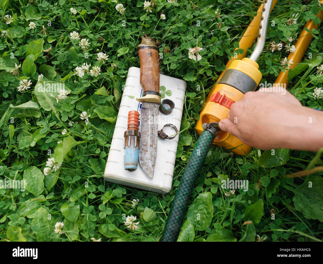 Male Hand Fixing A Garden Hose Laid On The Grass Work Tools And Hose Clamps Spread Out Around Stock Photo Alamy