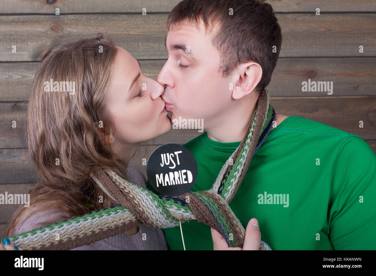 Love couple kisses wrapped in a scarf and shows funny icon on a stick with just married inscription, wooden background. Fun photo props and accessorie Stock Photo - Alamy Love couple kisses wrapped in a scarf and shows funny icon on a stick with just married inscription, wooden background. Fun photo props and accessorie Stock Photo - Alamy
