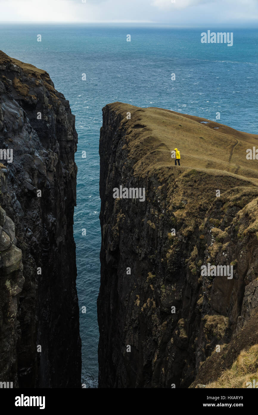 Hiker close to the high cliffs on the westcoast of Sandvík. Island of Suðuroy. Faroe Islands Stock Photo