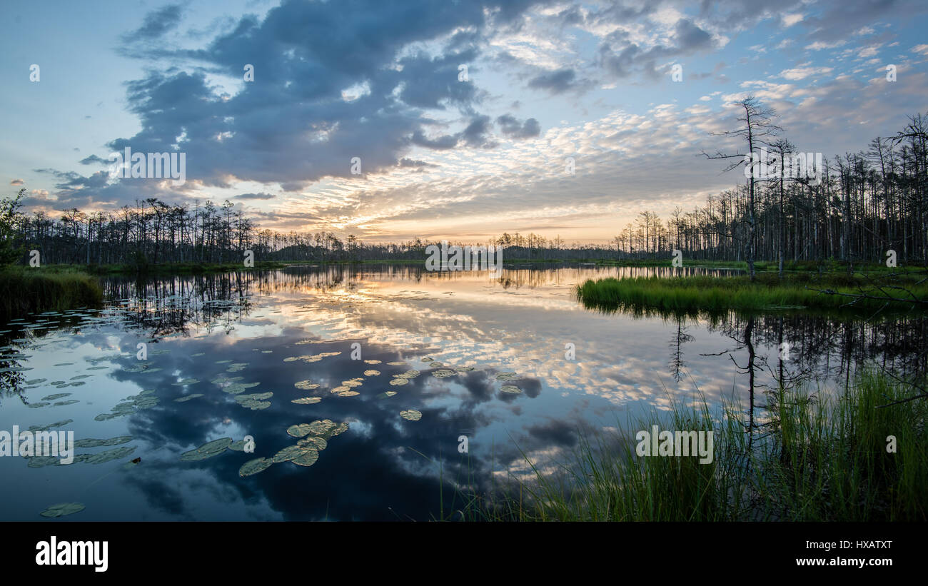 reflections in the lake water at sunrise with clouds and dramatic ...