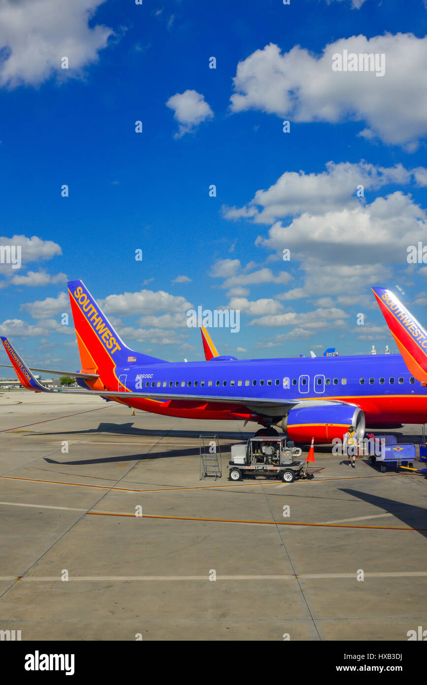 View of parked commerical airplanes at gates being serviced and having luggage loadied in preparation for flight Stock Photo
