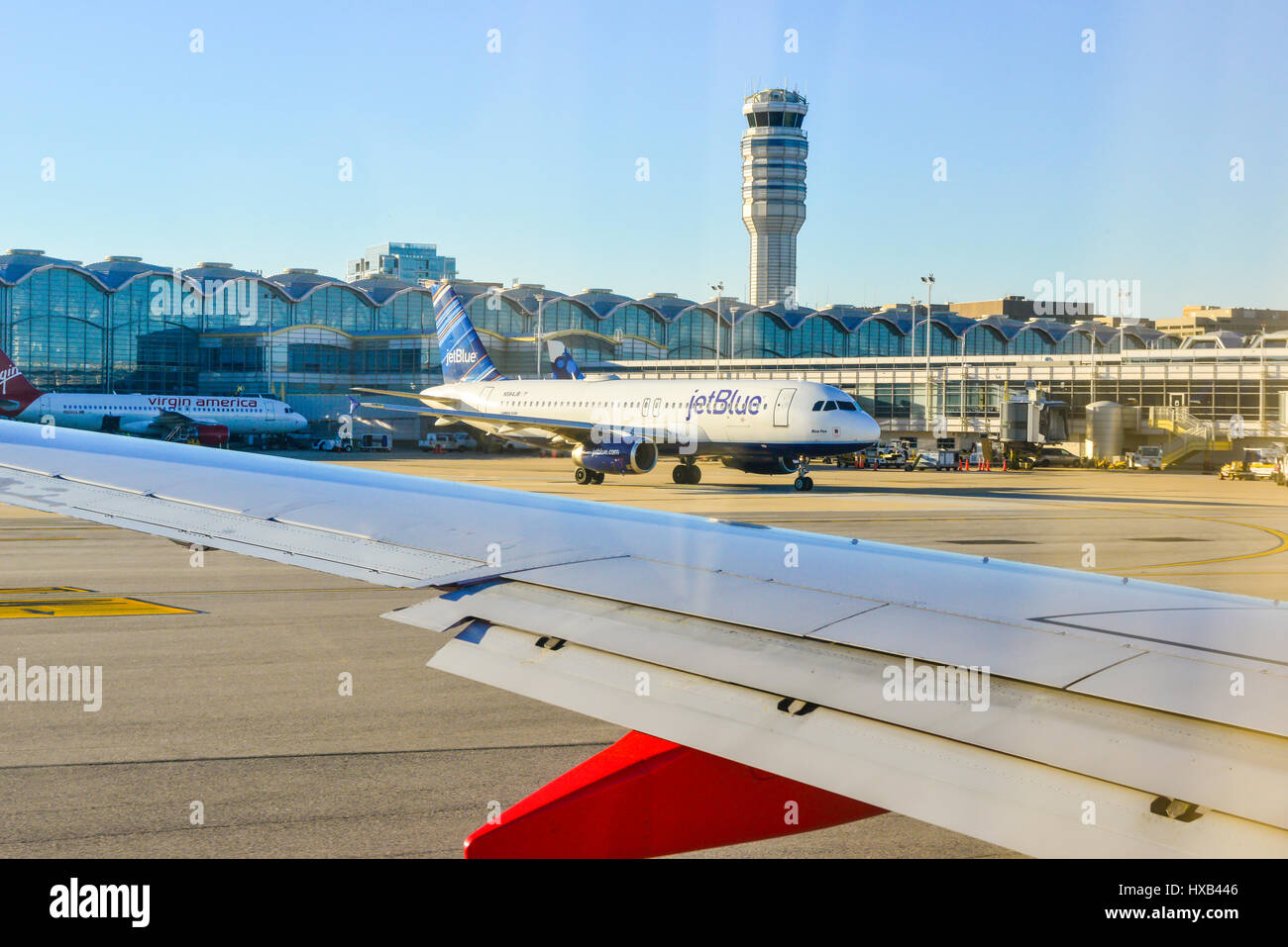 View of the Tampa, Florida airport terminal and control tower from taxiing Southwest Airlines jet on runway with a JetBlue airplane leaving gate Stock Photo