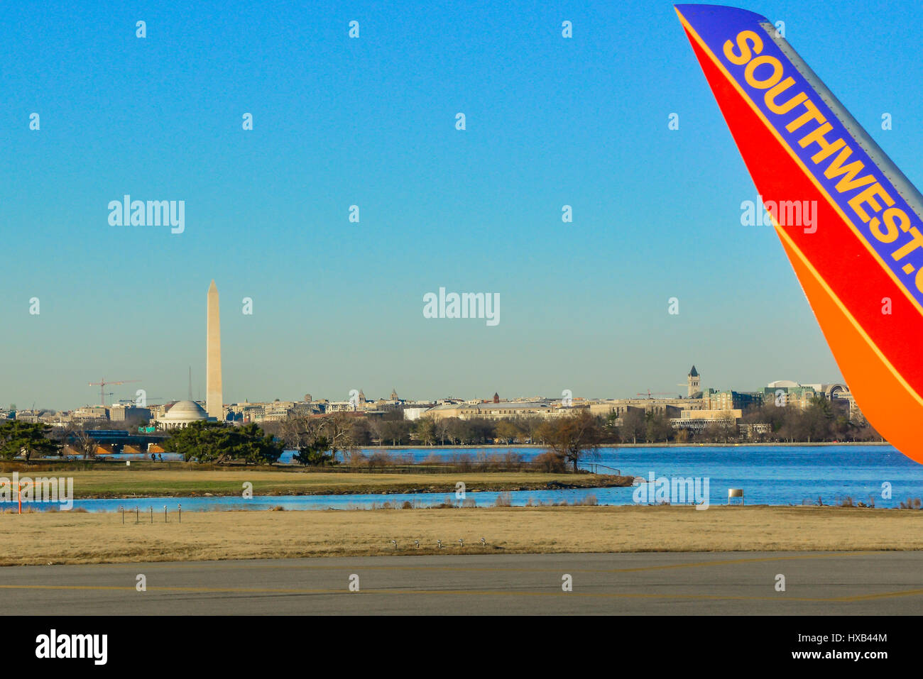The tip of a Southwest airlines wing is seen in foreground on the taxiway of Reagan National Airport with the Washington Monument in distance, DC. Stock Photo
