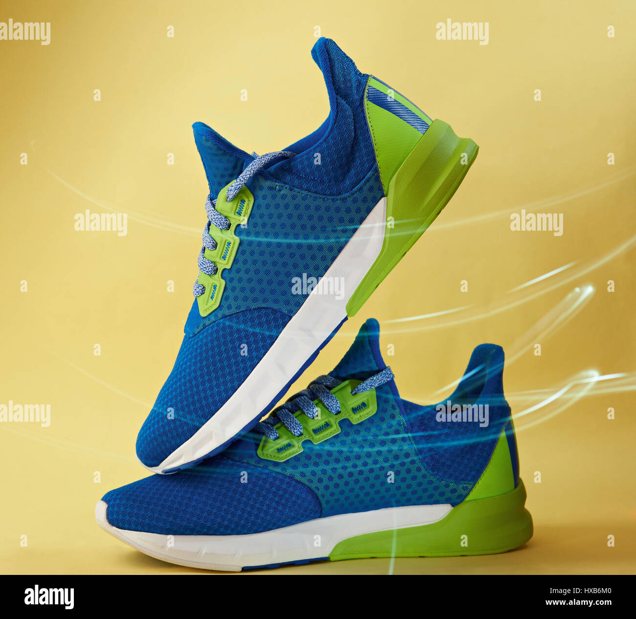 Pair of blue colorful running shoes with wind effect on yellow background. Fast runnning shoes Stock Photo