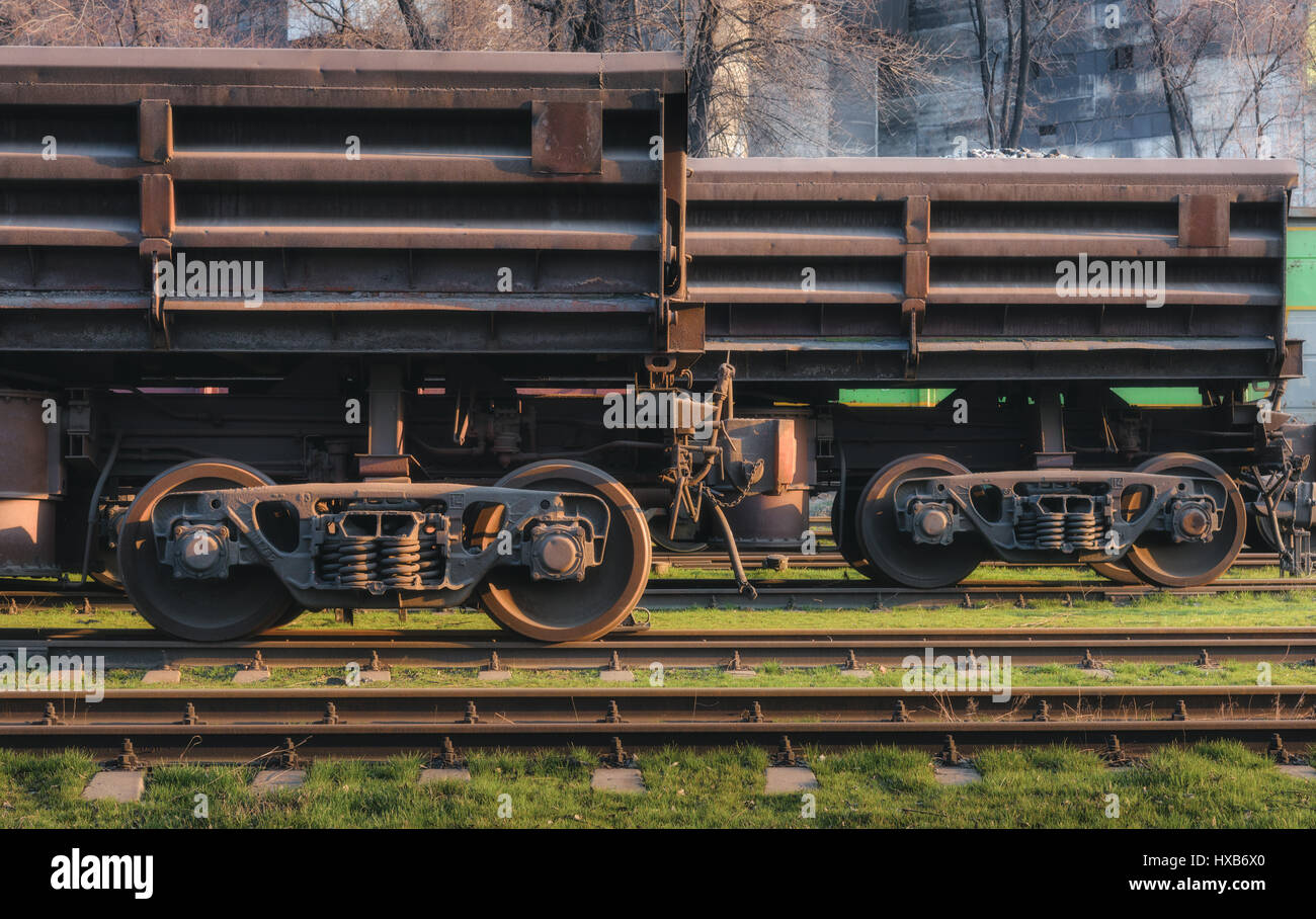 Freight wagons on the railway station and train against metallurgical plant at sunset. Industrial view. Close-up. Railroad in the evening. Railway pla Stock Photo