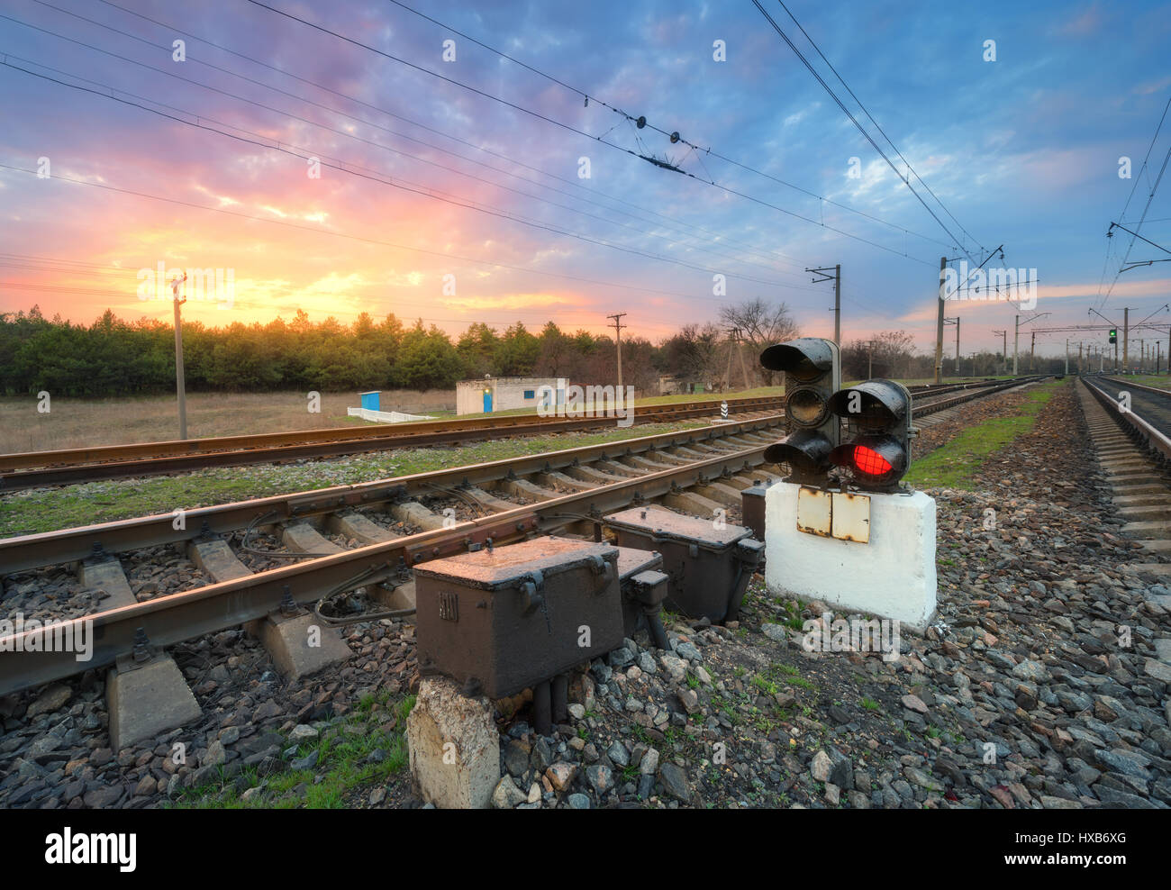Railway station with semaphore and beautiful bright cloudy sky at sunset. Colorful industrial landscape. Railroad. Railway platform with traffic light Stock Photo