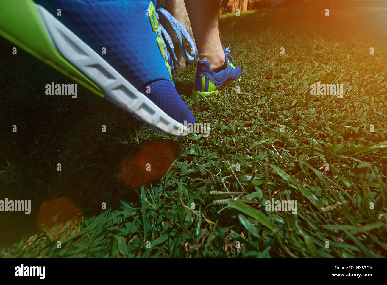 Walking on blue run shoes closeupon green grass background. Runner
