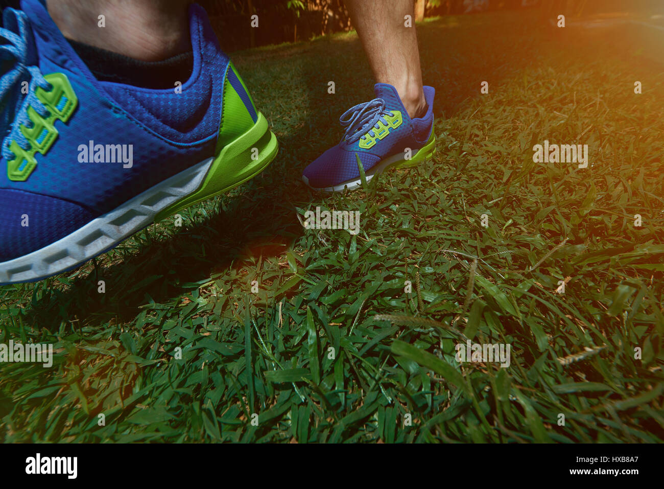 Man making step on blur run shoes on green grass park background. Man