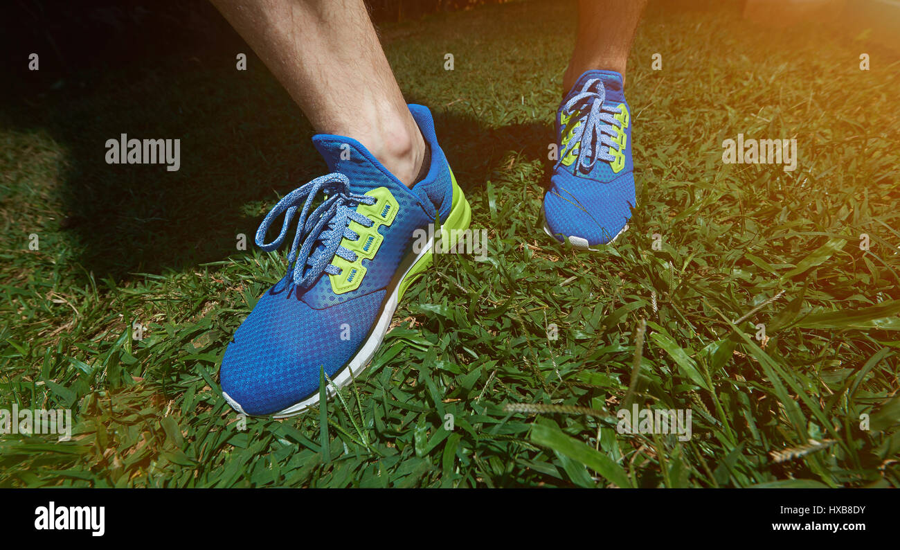 Modern run blue shoes closeup on green grass background. Man feet in