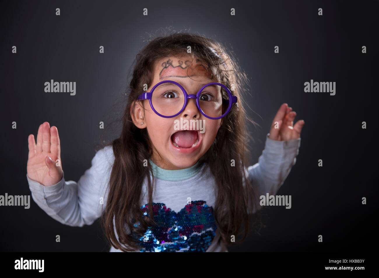 Portrait of a funny four years girl with glasses and makeup making