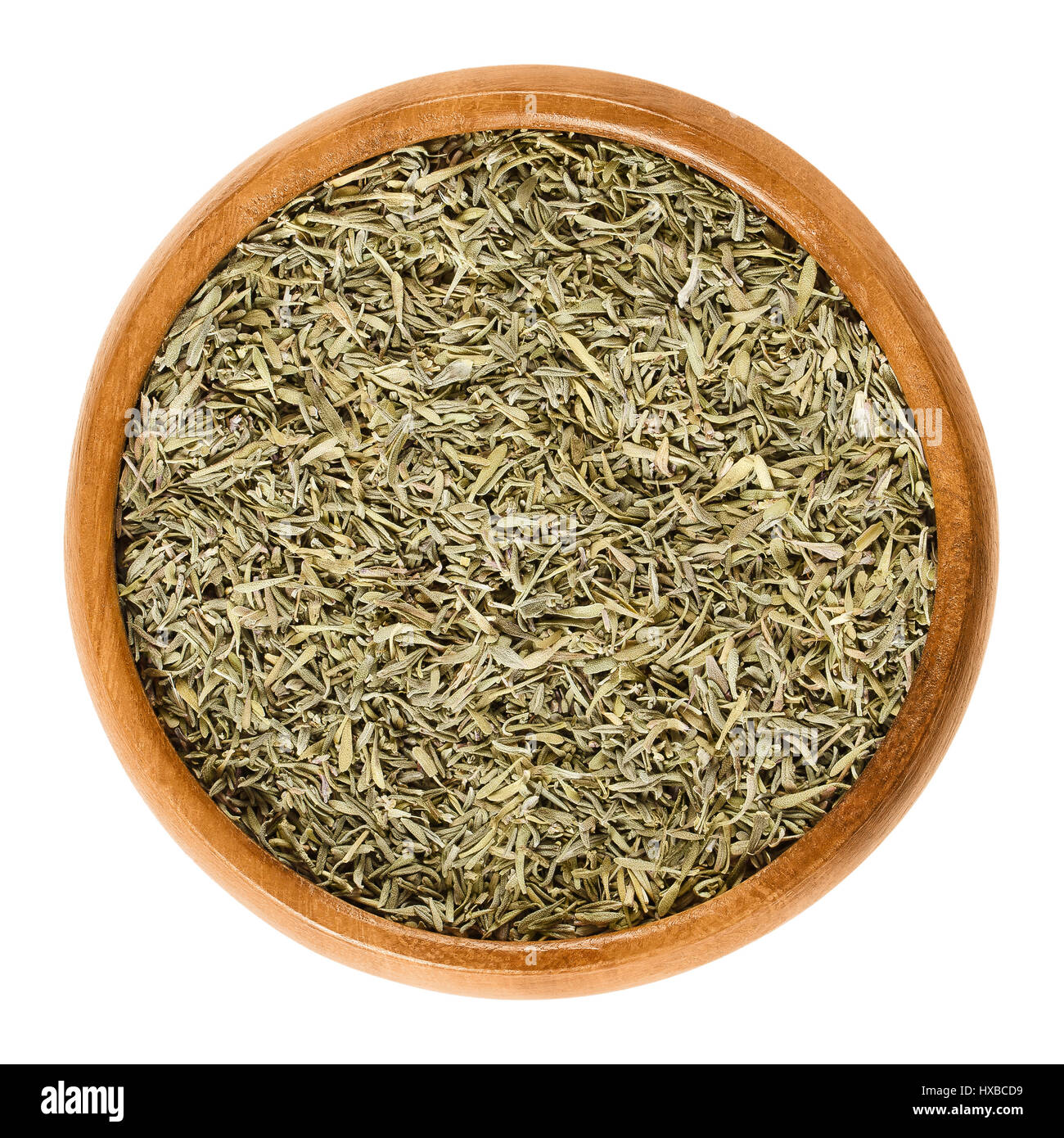 Dried thyme in wooden bowl. Minced stems. Herb with culinary and medicinal uses. Thymus vulgaris is a relative of oregano. Isolated macro photo. Stock Photo