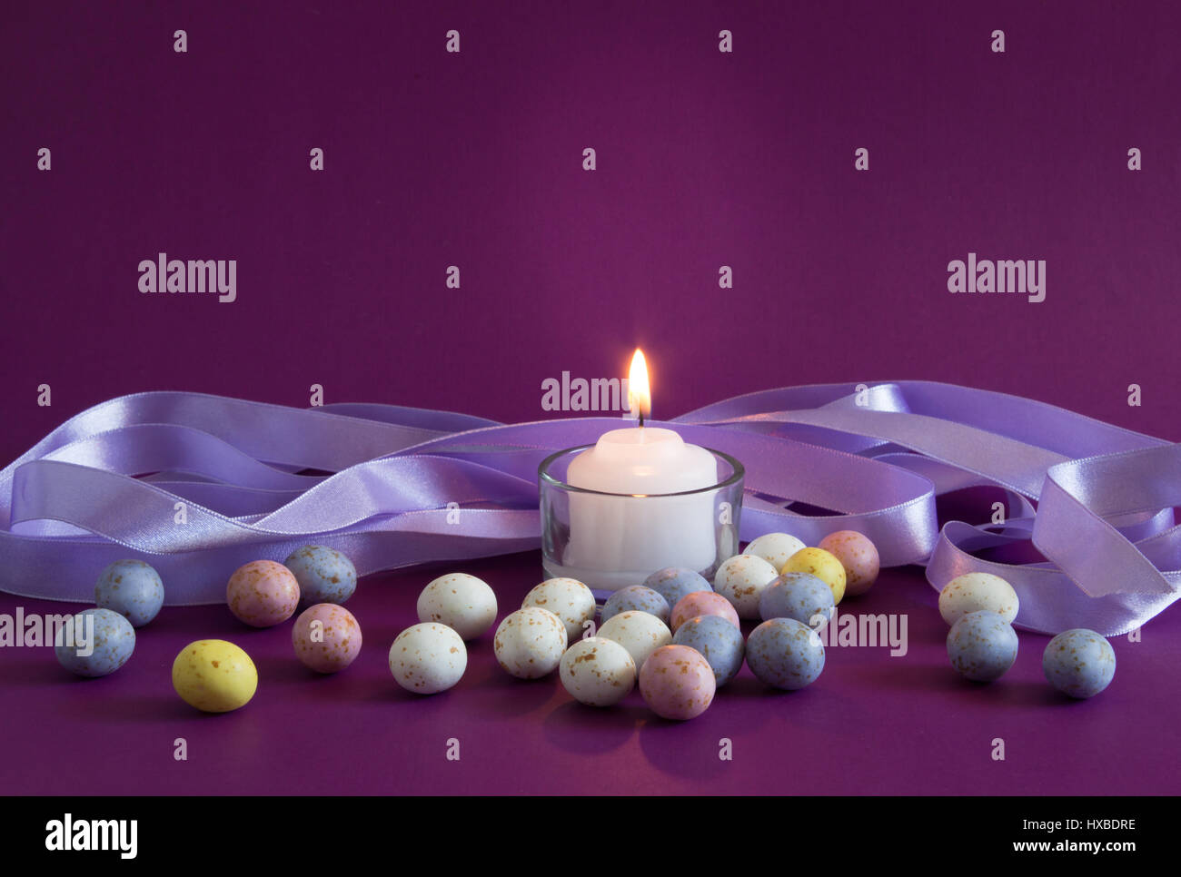 Violet Easter egg background with lit candle and small speckled