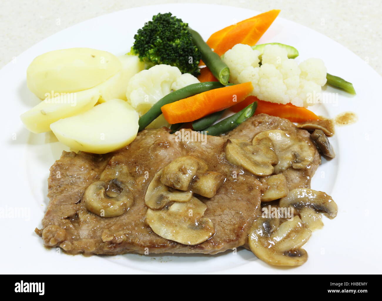 Braised beef and mushrooms in gravy with a steamed vegetable side Stock Photo