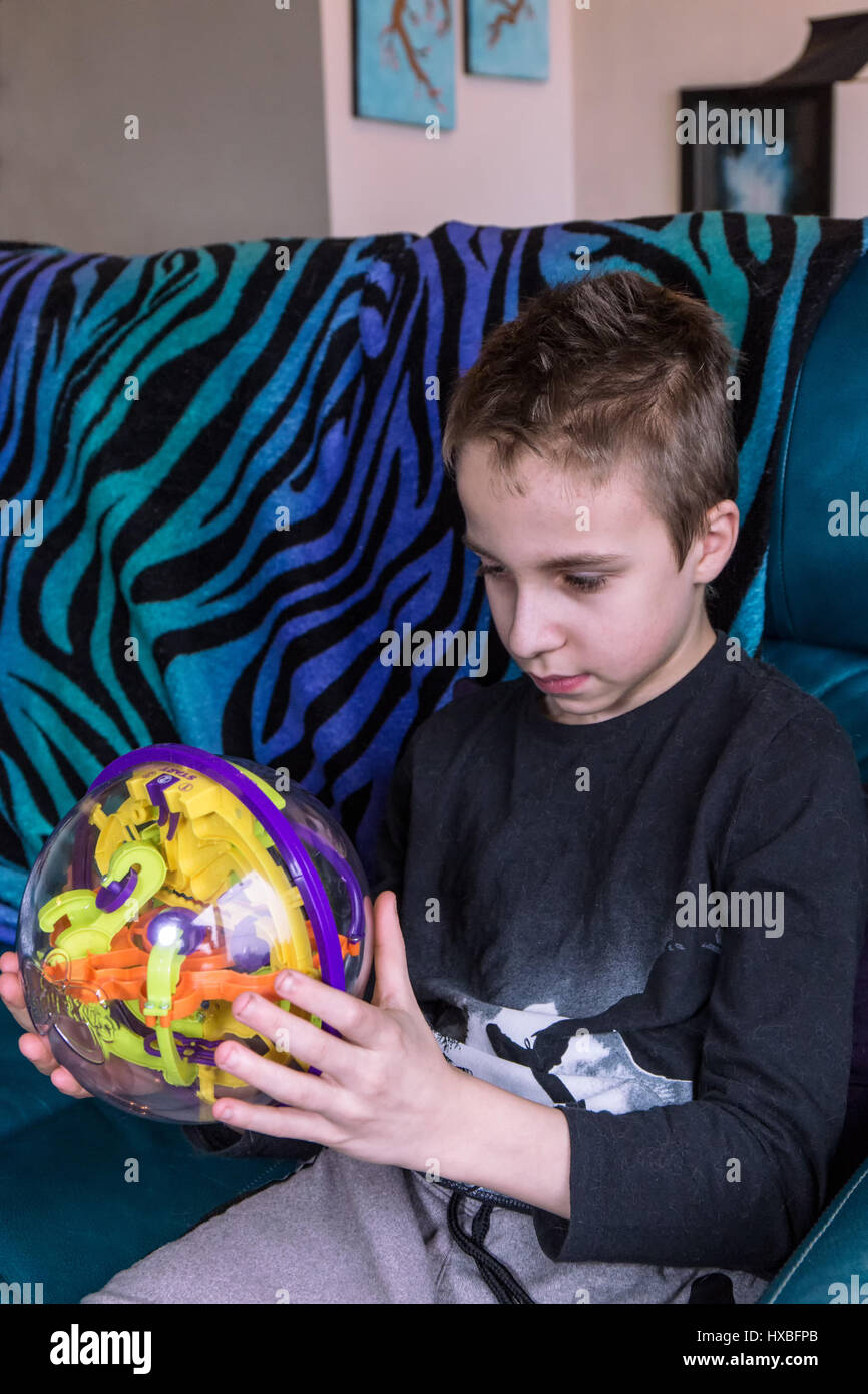 Fourteen year old boy trying to solve a puzzle ball Stock Photo