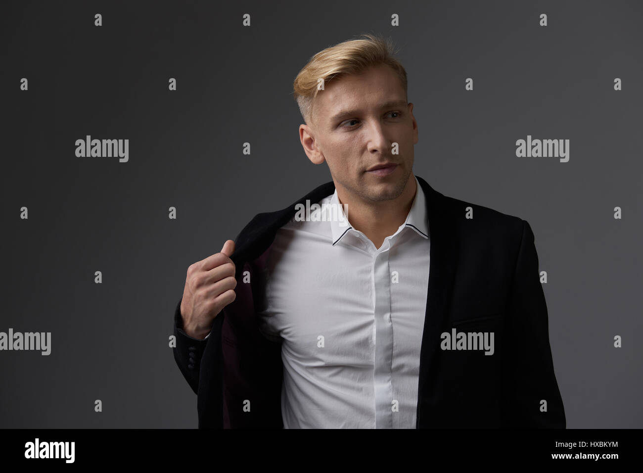 Portrait of a handsome young man smiling against gray background ...