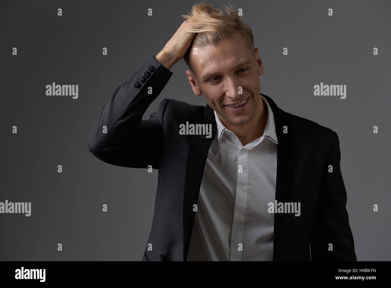 Portrait of a handsome young man smiling against gray background ...