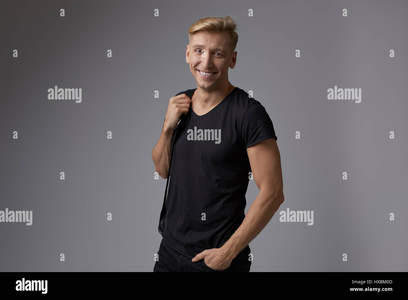 Portrait of a handsome young man smiling against gray background ...