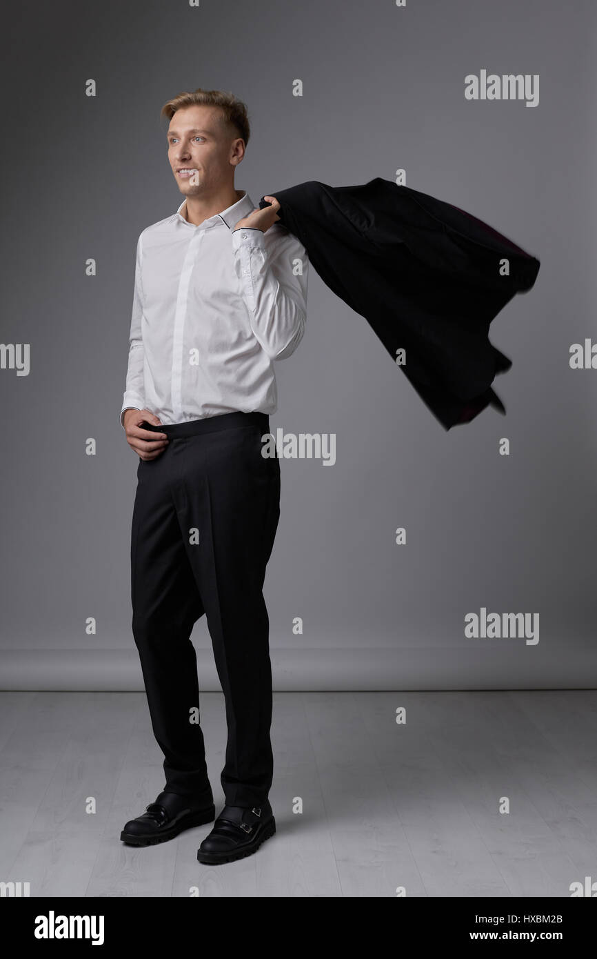 Portrait of a handsome young man smiling against gray background ...