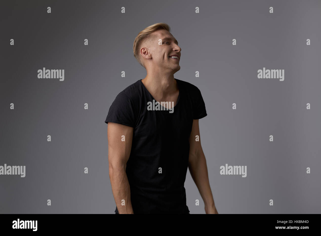 Portrait of a handsome young man smiling against gray background ...