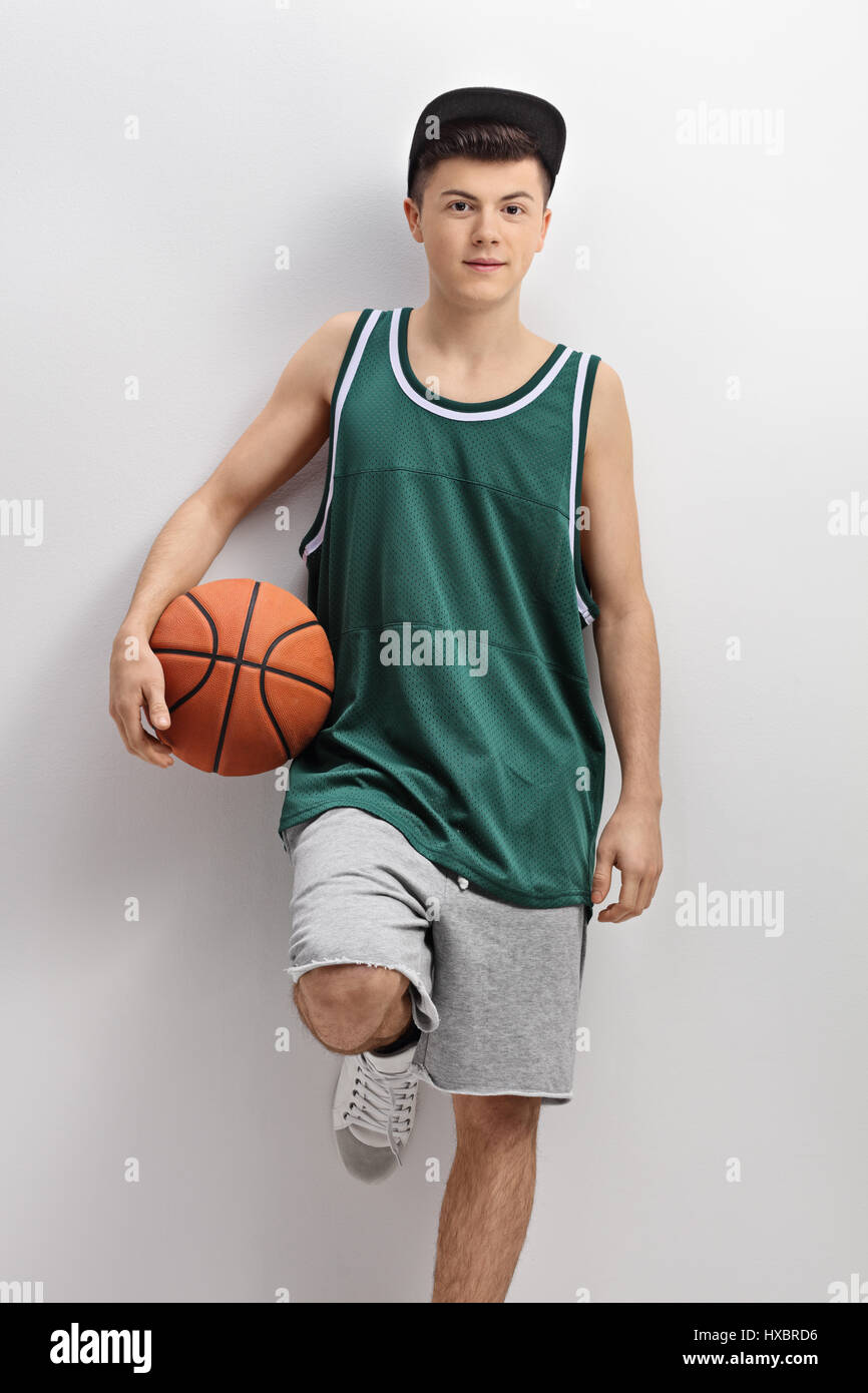 Teenager in a green jersey holding a basketball and leaning on a wall Stock  Photo - Alamy