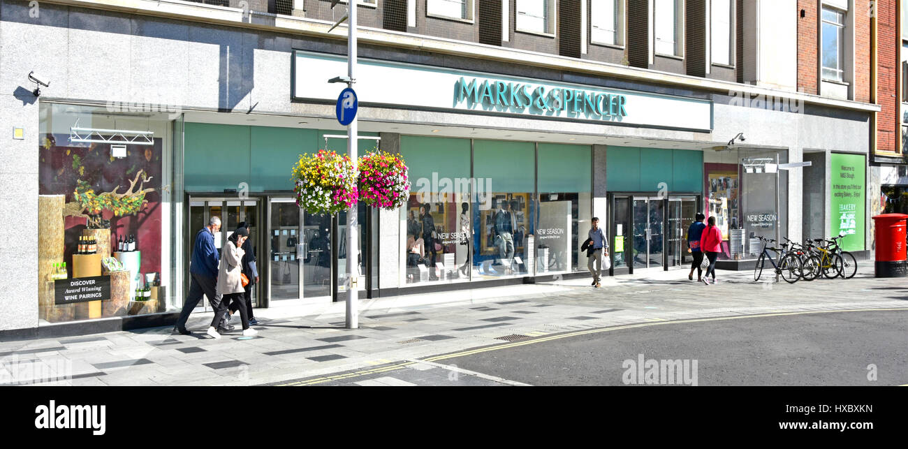 Marks and Spencer M&S shop front windows in high street retail shopping centre shoppers walking along pedestrian paved over road Slough Berkshire UK Stock Photo